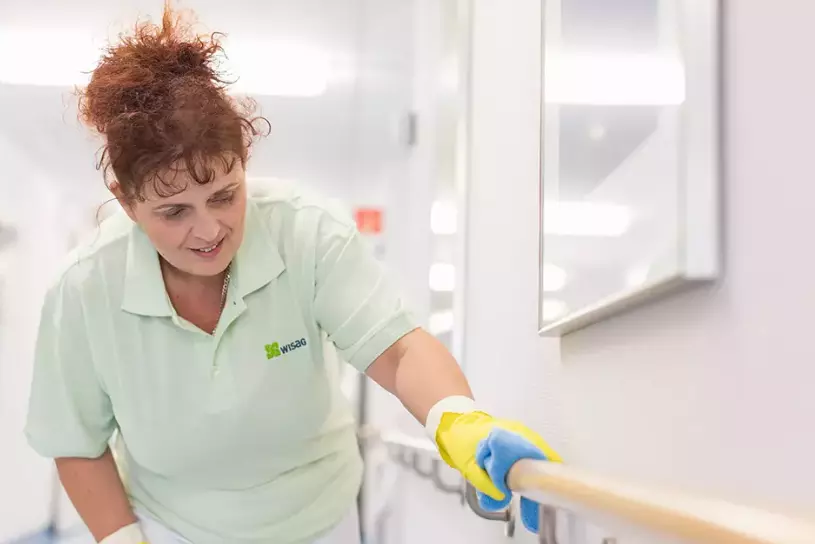 WISAG Mitarbeiterin beim Reinigen des Geländers in einem Krankenhausflur